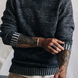 fit model adjusting his sleeves in The Headland Sweater in Coal Heather