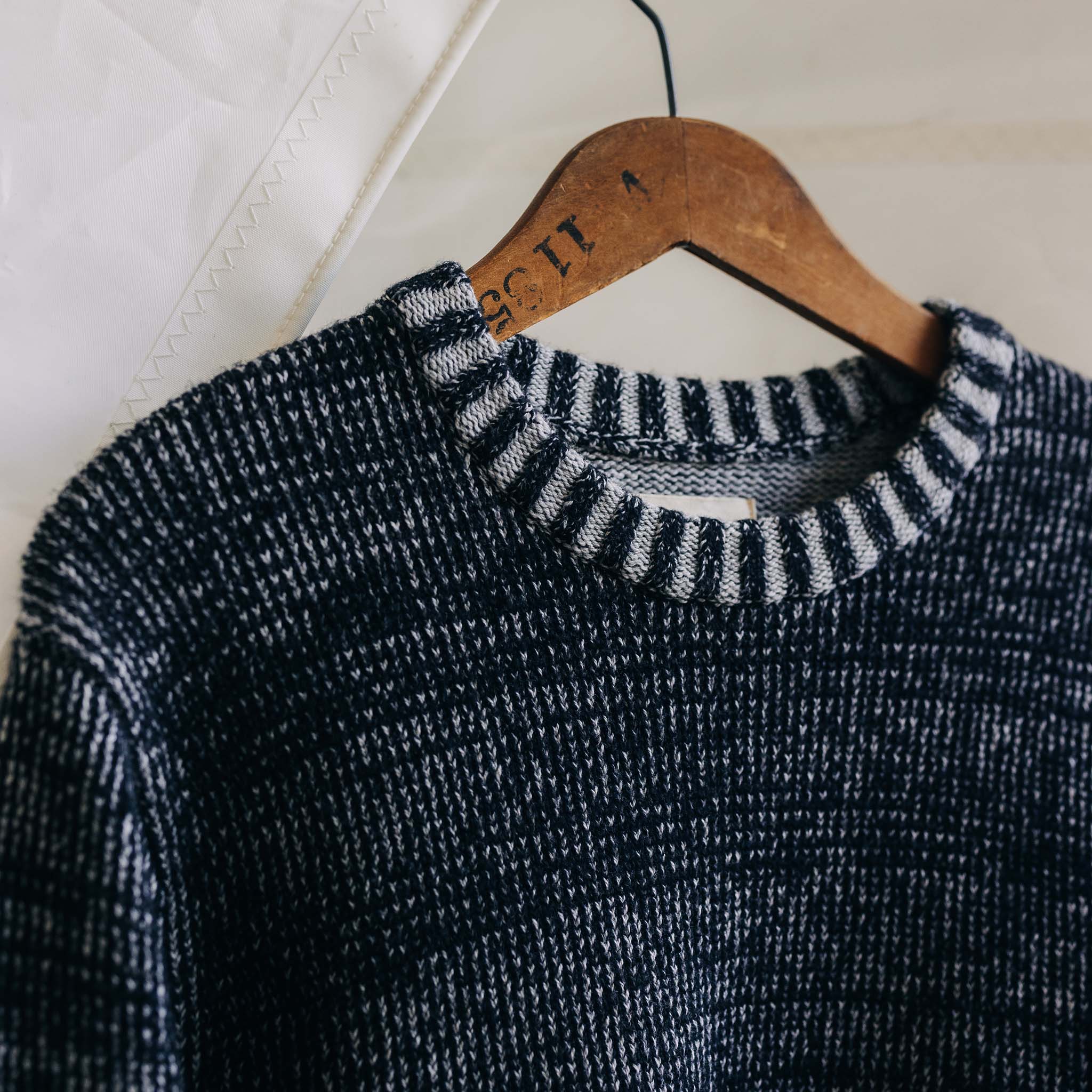 The Headland Sweater in Coal Heather on a hanger, Knits by Taylor Stitch