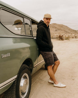 fit model leaning against a car wearing The Apres Hoodie in Black Indigo Terry, Knits by Taylor Stitch