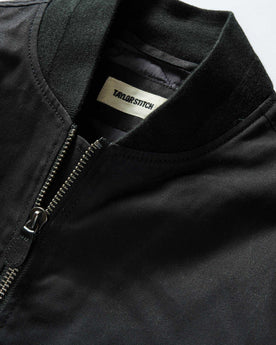 material shot of the ribbed neck opening on The Insulated Bomber Jacket in Coal Dry Wax, Outerwear by Taylor Stitch