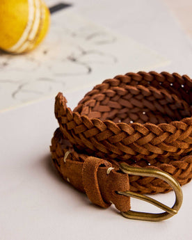 editorial image of The Braided Belt in Tan Suede rolled up next to a ball, Accessories by Taylor Stitch