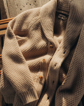 editorial image of The Fisherman Shawl Cardigan in Heather Oat Merino on a bench, Knits by Taylor Stitch