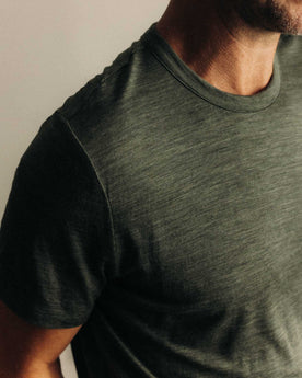 fit model leaning against the wall wearing The Merino Tee in Heather Army, Knits by Taylor Stitch