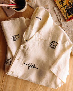 editorial flatlay of The Short Sleeve Davis Shirt in Embroidered Natural on the ground of a studio , Wovens by Taylor Stitch