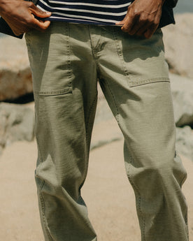 fit model sitting wearing The Surplus Pant in Field Olive Reverse Sateen, Bottoms by Taylor Stitch