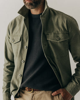 fit model sitting wearing The Surplus Shirt in Field Olive Reverse Sateen, Wovens by Taylor Stitch