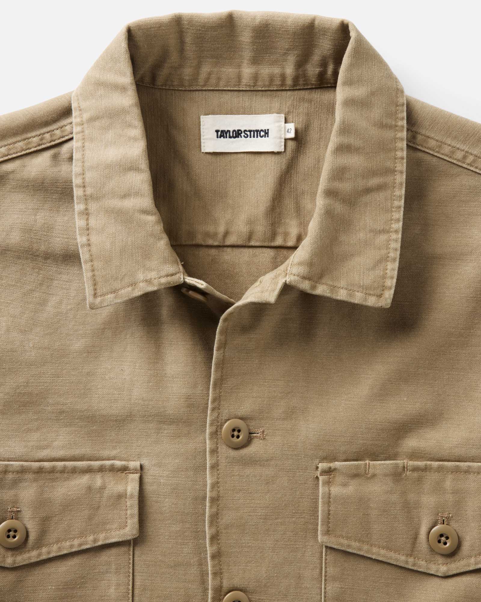 fit model leaning against the wall wearing The Surplus Shirt in Khaki Reverse Sateen, Wovens by Taylor Stitch