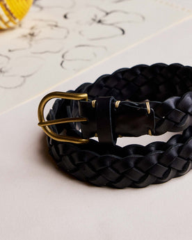 editorial image of The Braided Belt in Black rolled up on paper, Accessories by Taylor Stitch