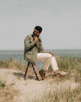 fit model sitting wearing The Surplus Jacket in Field Olive Reverse Sateen, Outerwear by Taylor Stitch