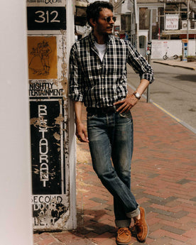 fit model leaning against the wall wearing The Jack in Rinsed Indigo Plaid Oxford, Wovens by Taylor Stitch