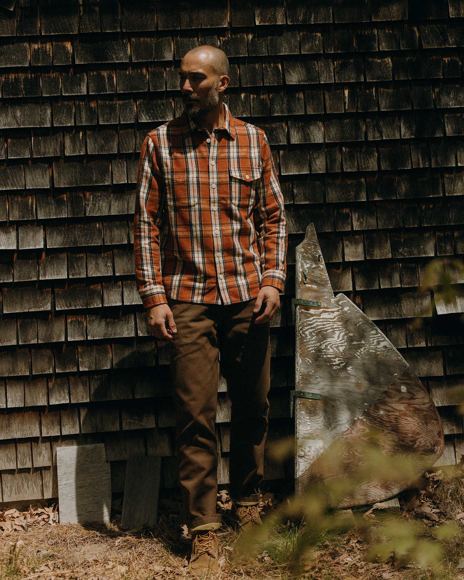 fit model leaning against the wall wearing The Crater Shirt in Brick Plaid, Wovens by Taylor Stitch