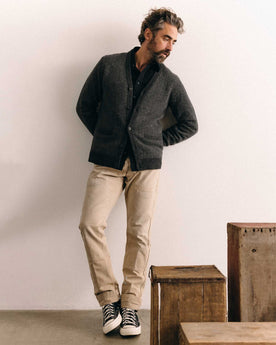 fit model leaning against a wall wearing The Eddy Cardigan in Heather Charcoal Herringbone, Knits by Taylor Stitch