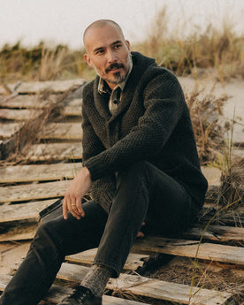 fit model sitting wearing The Fisherman Shawl Cardigan in Heather Coal Merino, Knits by Taylor Stitch