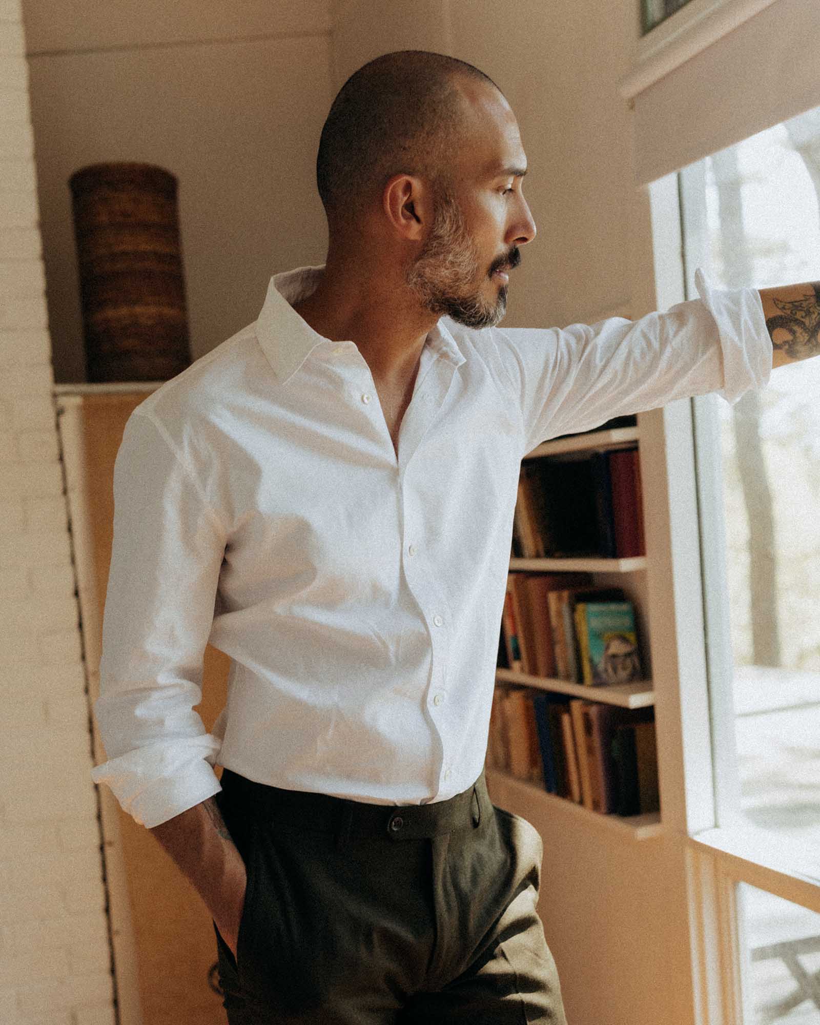 fit model leaning against a window wearing The Hyde Shirt in White Pinpoint Oxford, Wovens by Taylor Stitch