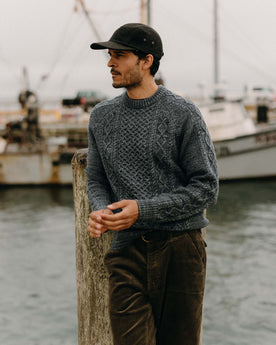 fit model leaning against a stick wearing The Orr Sweater in Marled Marine Merino, Knits by Taylor Stitch