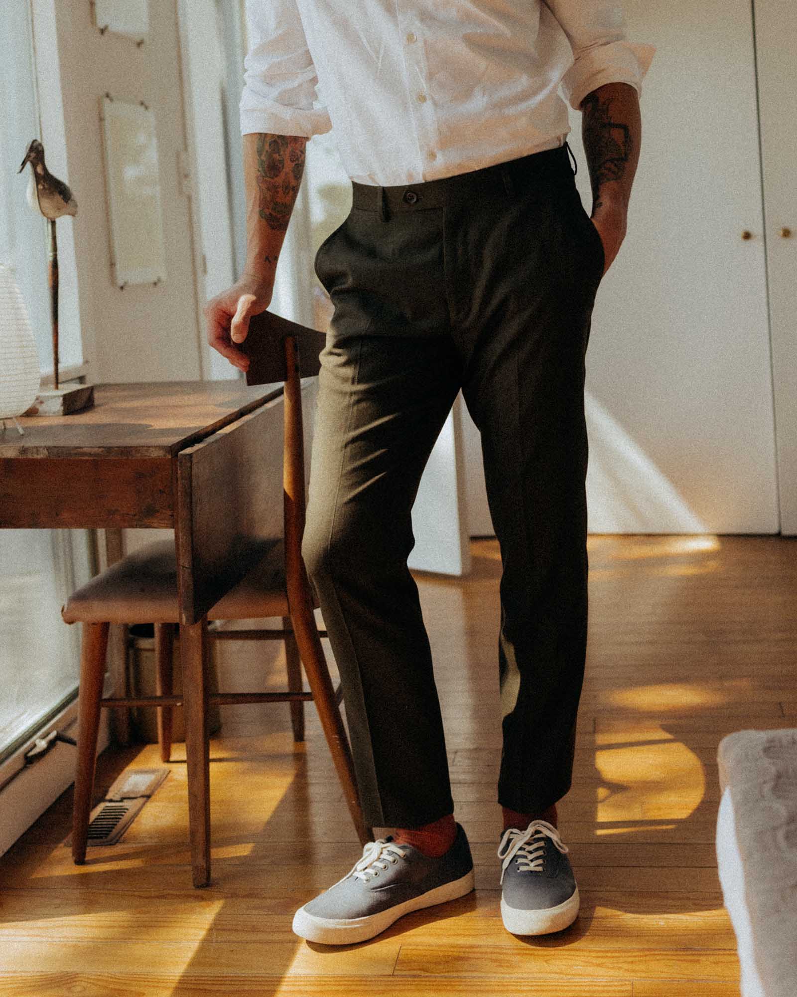 fit model leaning against a chair wearing The Stevens Trouser in Black Olive Wool Flannel, Bottoms by Taylor Stitch