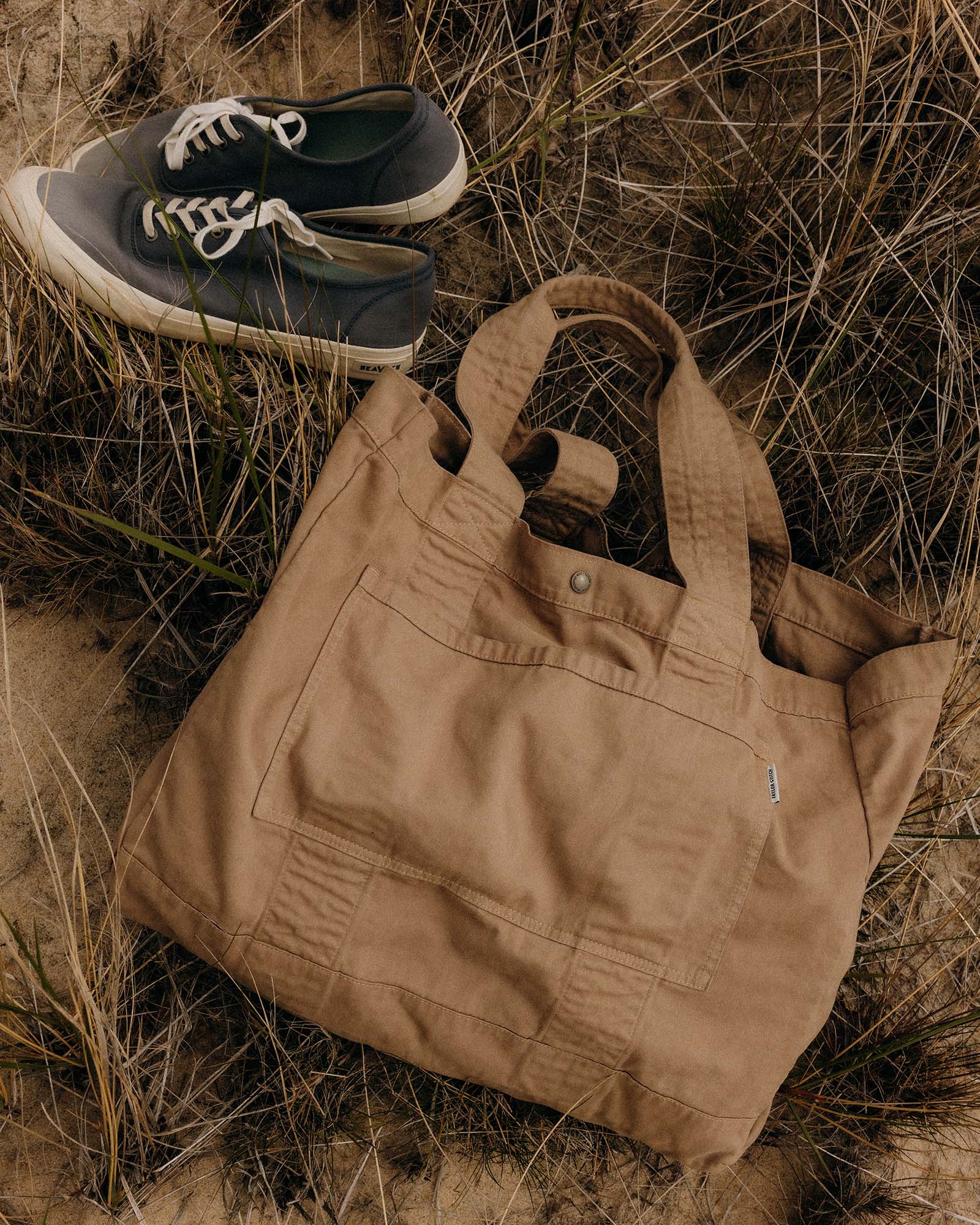editorial image of The Foundation Tote in Organic Khaki on the sand, Accessories by Taylor Stitch