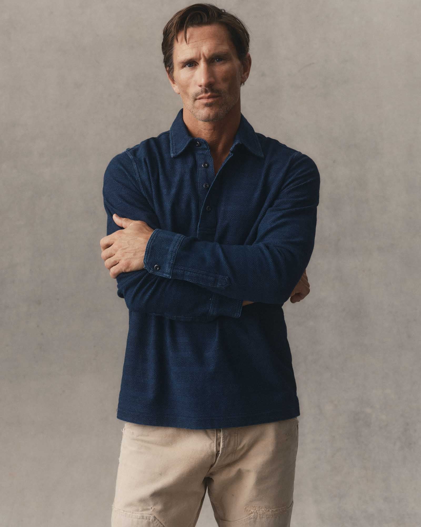 fit model leaning against a table wearing The Long Sleeve Polo in Indigo Knit Stripe, Knits by Taylor Stitch