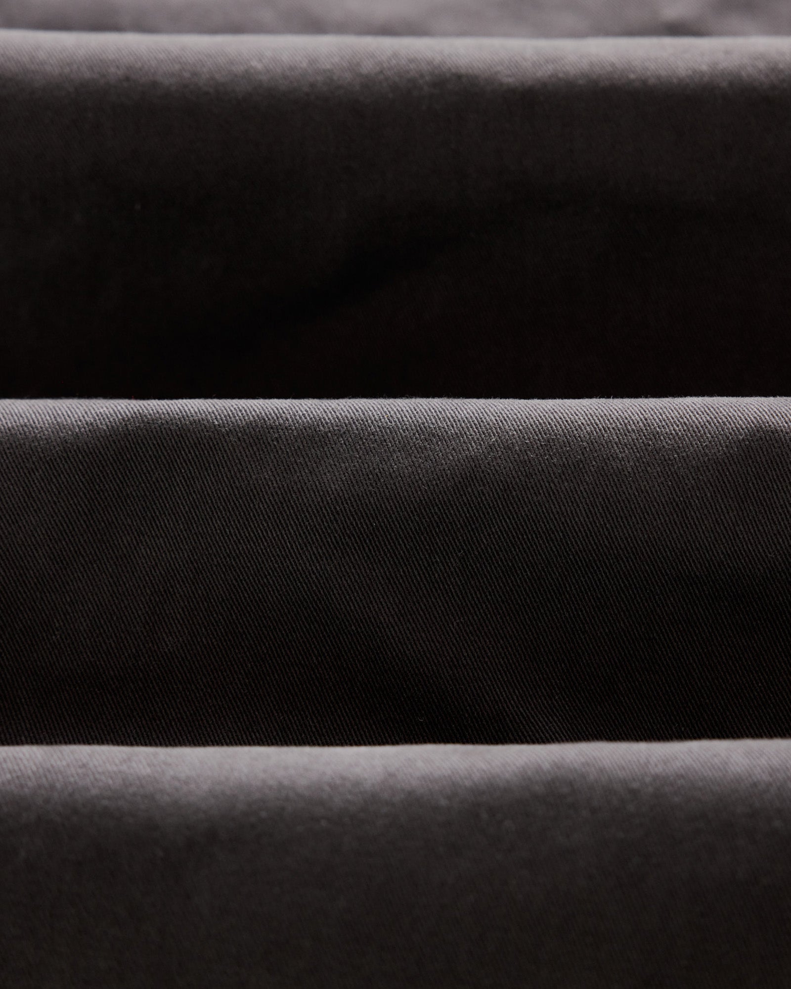 material shot of the twill texture on The Slim Foundation Pant in Organic Faded Black, Bottoms by Taylor Stitch