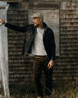 fit model leaning against the wall wearing The Shop Shirt in Rinsed Indigo Selvedge, Wovens by Taylor Stitch