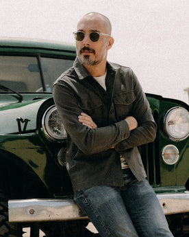 fit model sitting wearing The Surplus Shirt in Faded Black Reverse Sateen, Wovens by Taylor Stitch