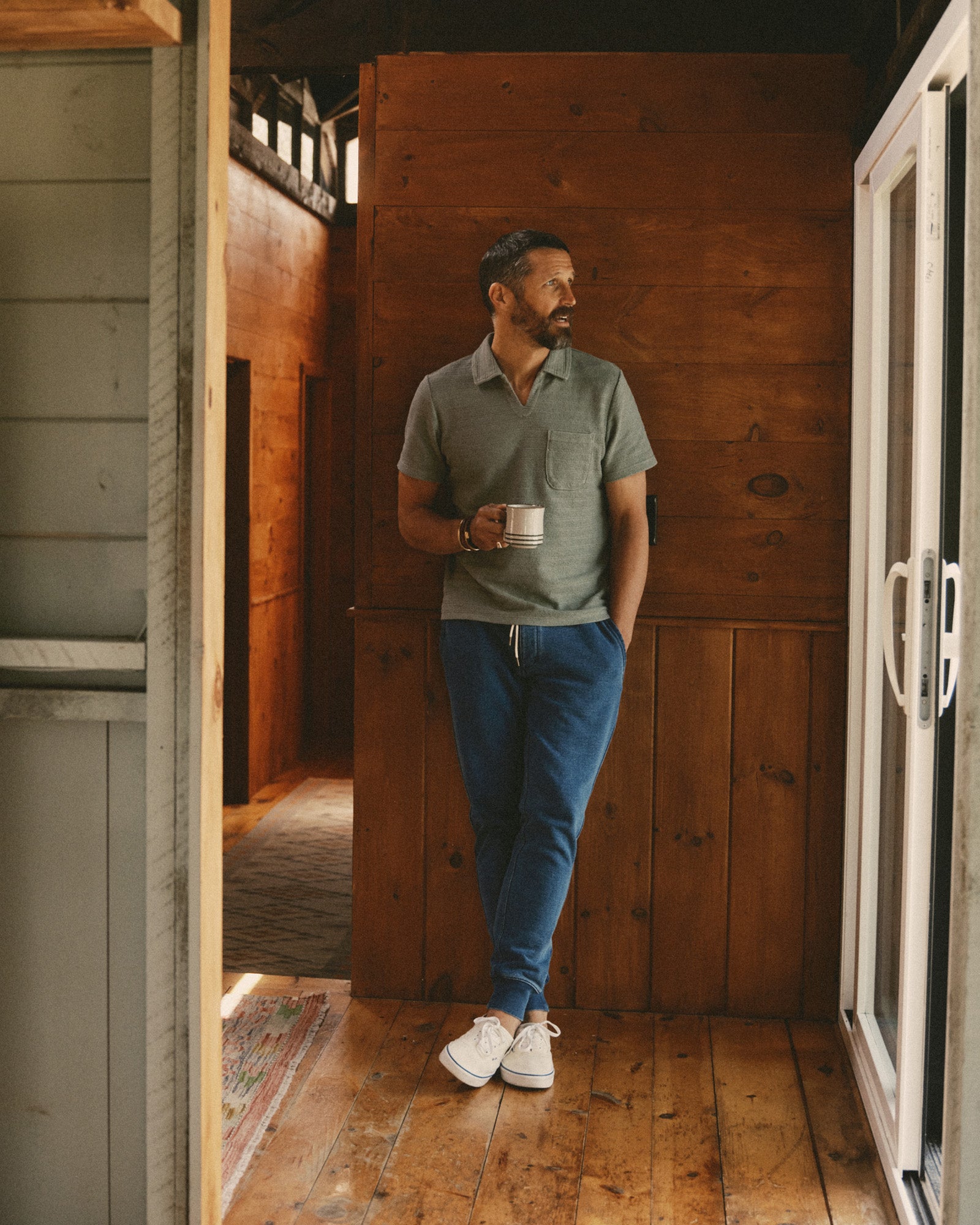 fit model leaning against a wall wearing The Meridian Polo in Faded Pine, Knits by Taylor Stitch