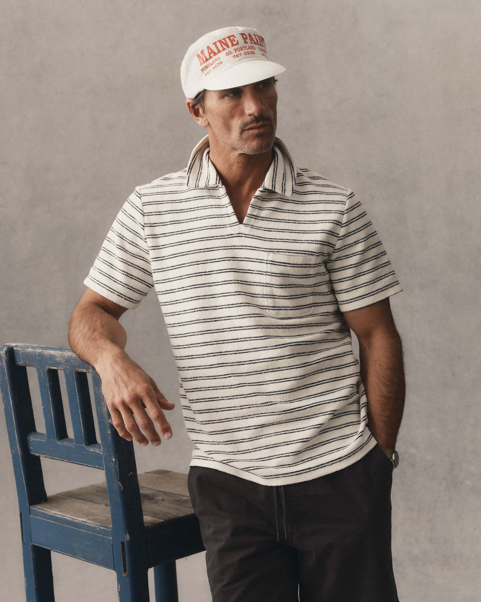 fit model leaning against a chair wearing The Meridian Polo in Marine Stripe, Knits by Taylor Stitch