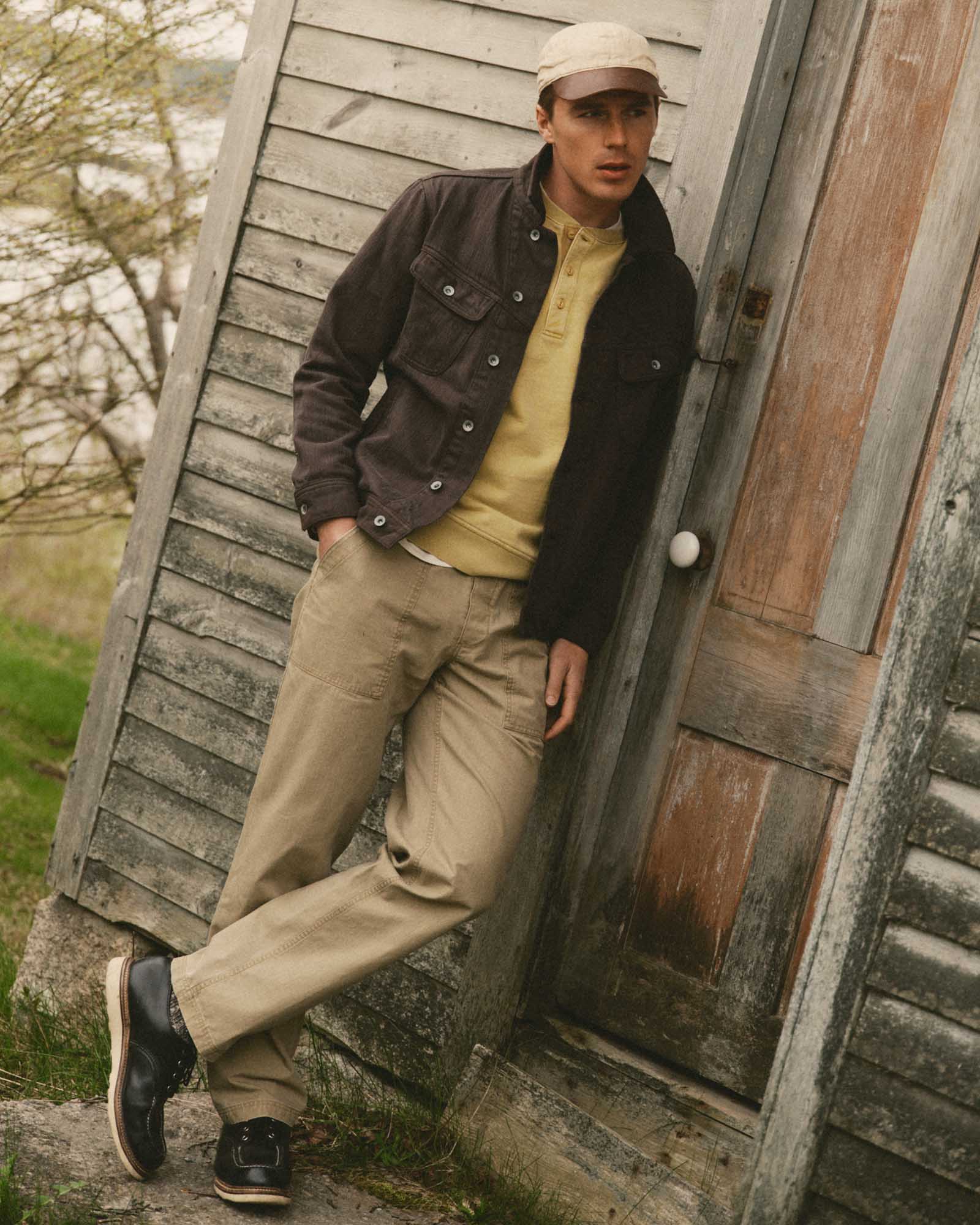 fit model leaning against the wall wearing The Breakwater Pant in Field Khaki Ripstop, Bottoms by Taylor Stitch