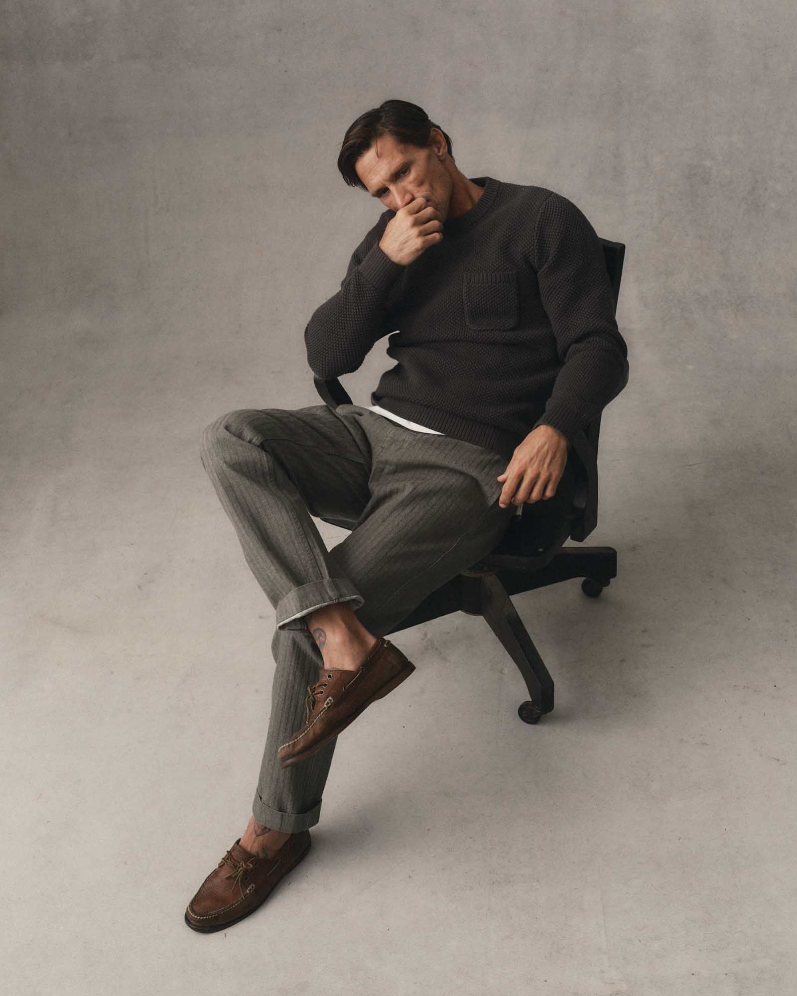 fit model sitting wearing The Crawford Crew Sweater in Charcoal, Sweaters by Taylor Stitch