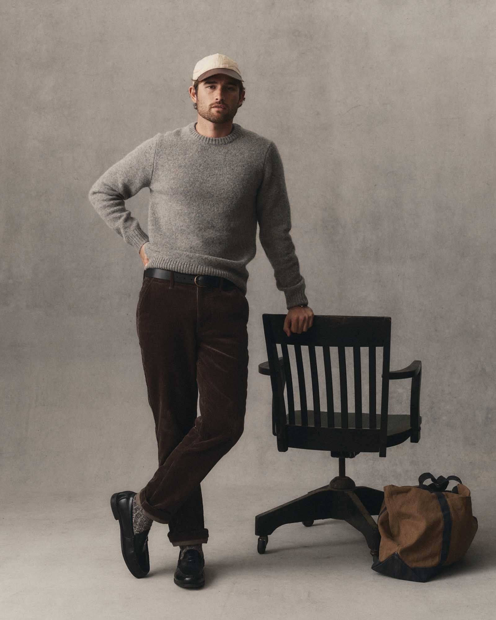 fit model leaning against a chair wearing The Eastmoor Sweater in Glen Wool, Knits by Taylor Stitch
