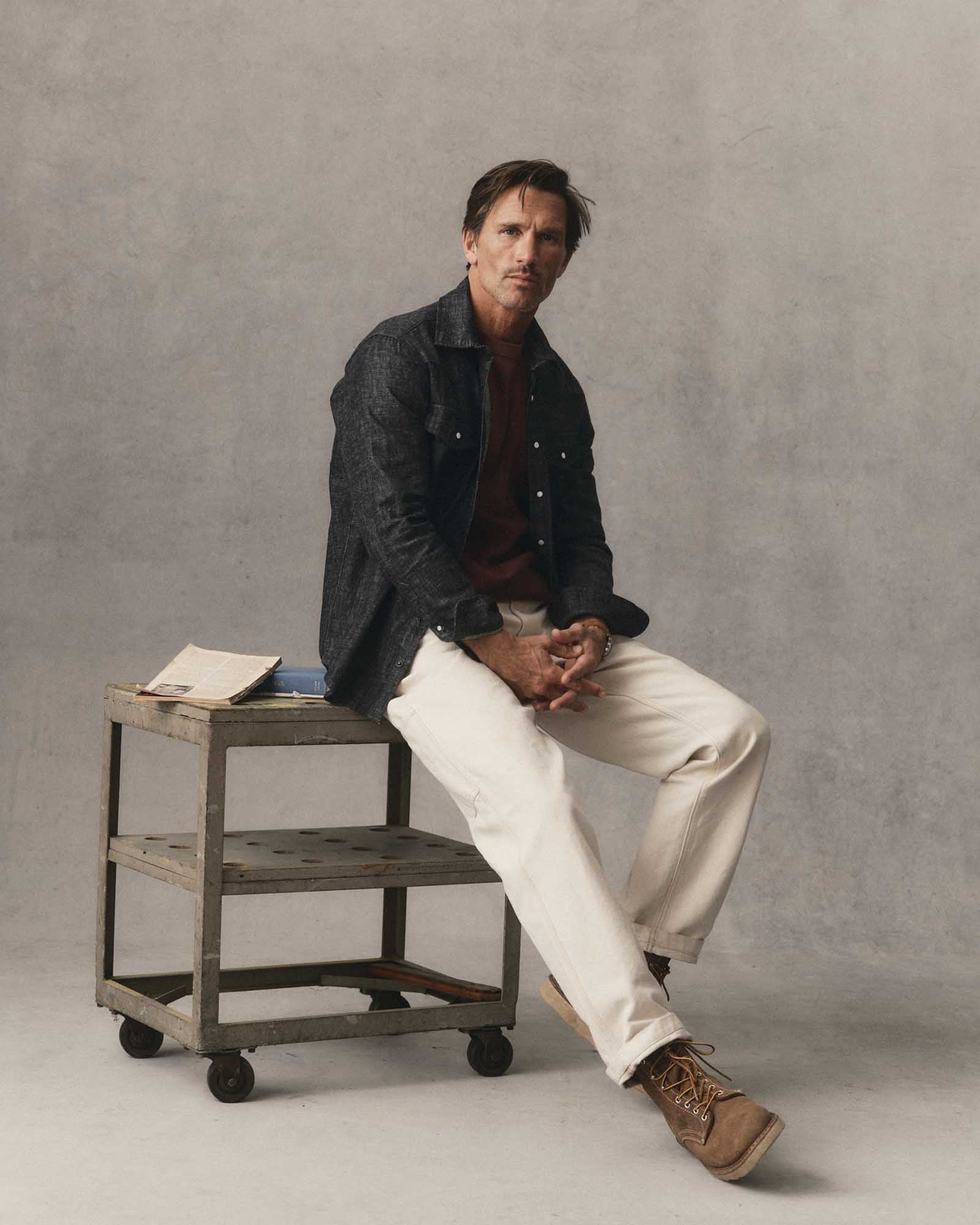 fit model sitting wearing The Glacier Shirt in Black Indigo Hemp Denim, Wovens by Taylor Stitch