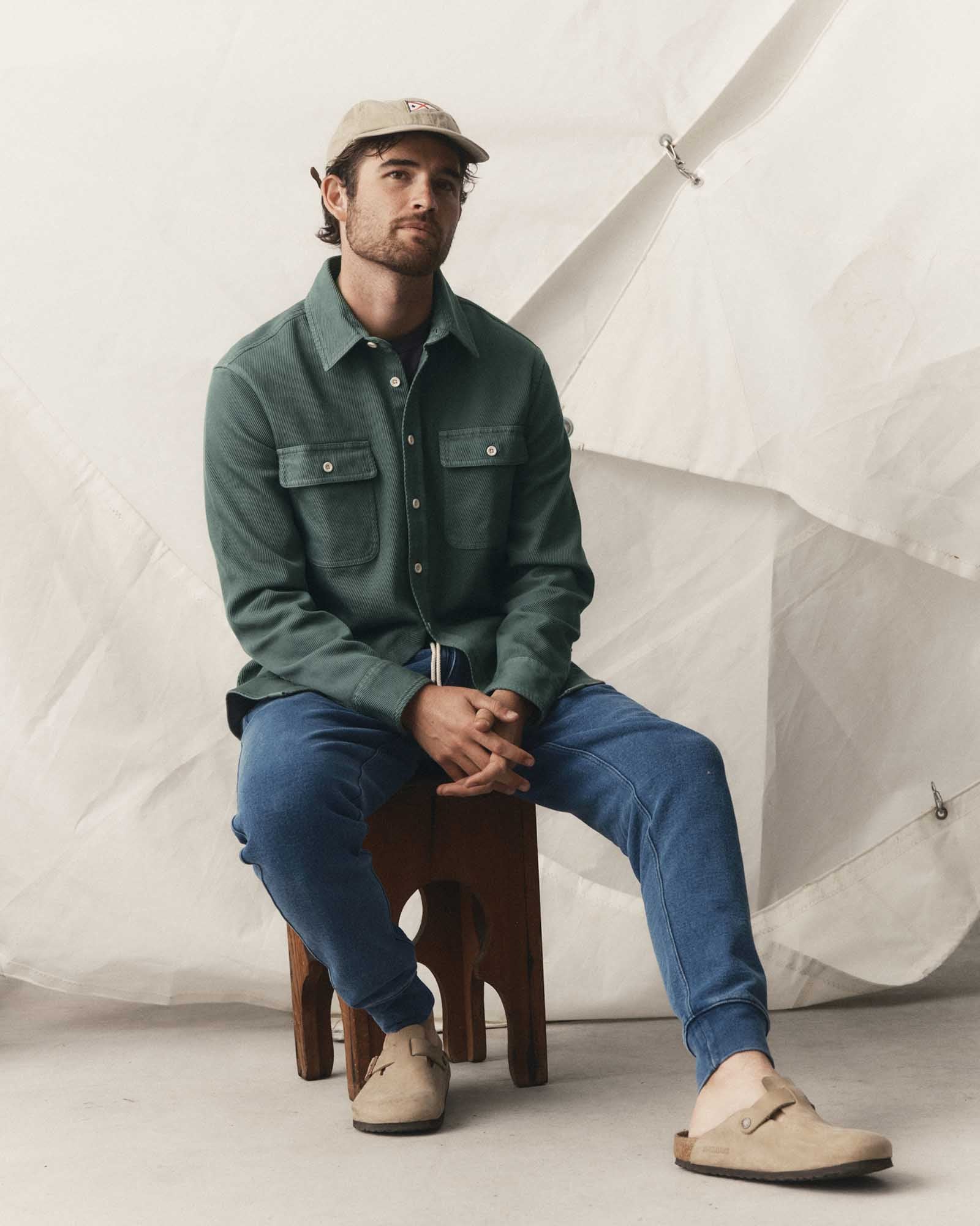 fit model sitting wearing The Ledge Shirt in Deep Sea Twill, Wovens by Taylor Stitch