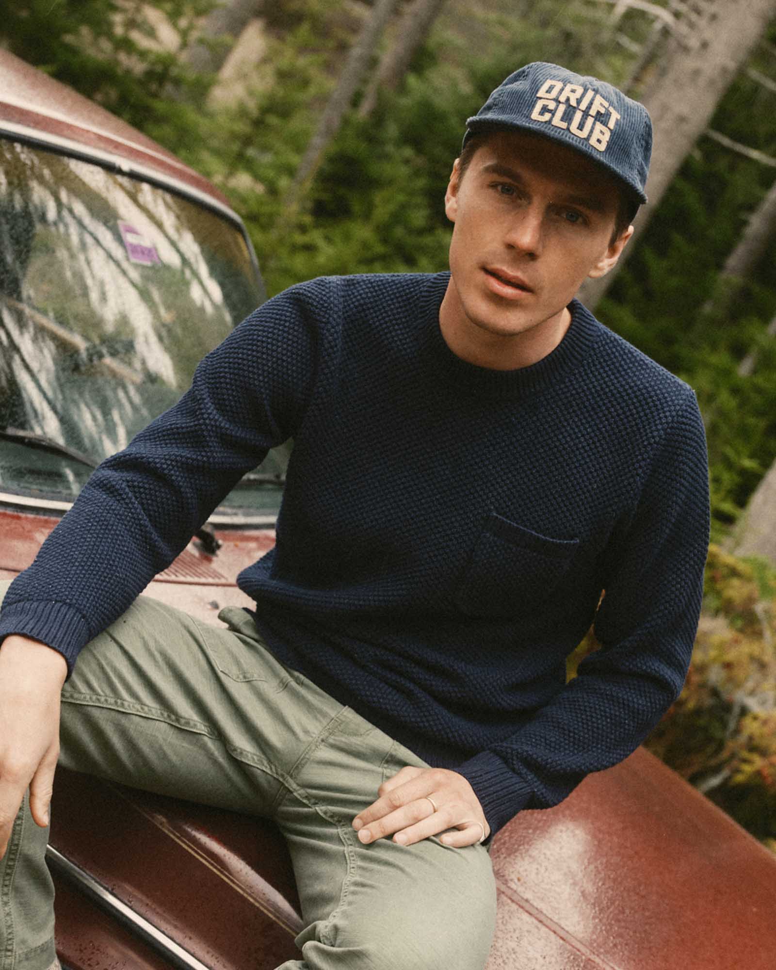 fit model sitting wearing The Mercer Cap in Drift Club, Accessories by Taylor Stitch