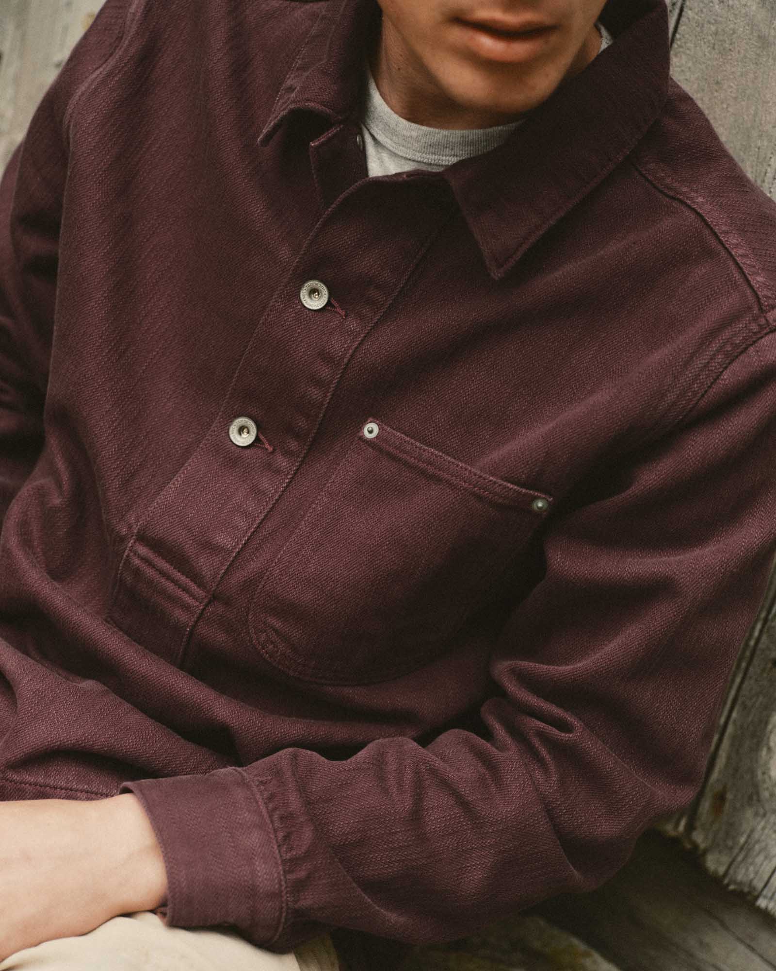 fit model sitting wearing The Milton Overshirt in Burgundy Slub Denim, Outerwear by Taylor Stitch