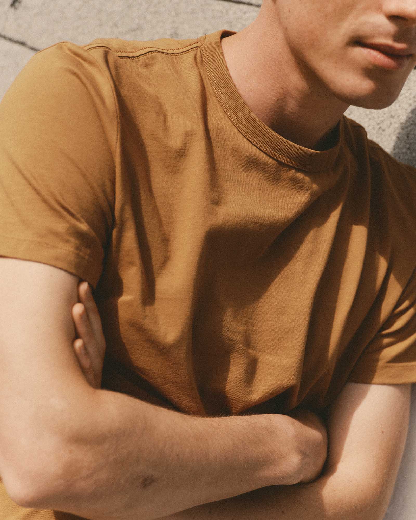 fit model with his arms crossed wearing The Regenerative Cotton Tee in Saffron, Knits by Taylor Stitch