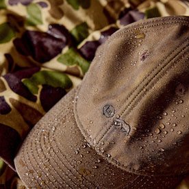 The Ball Cap in Dark Khaki Waxed Canvas with water droplets on it