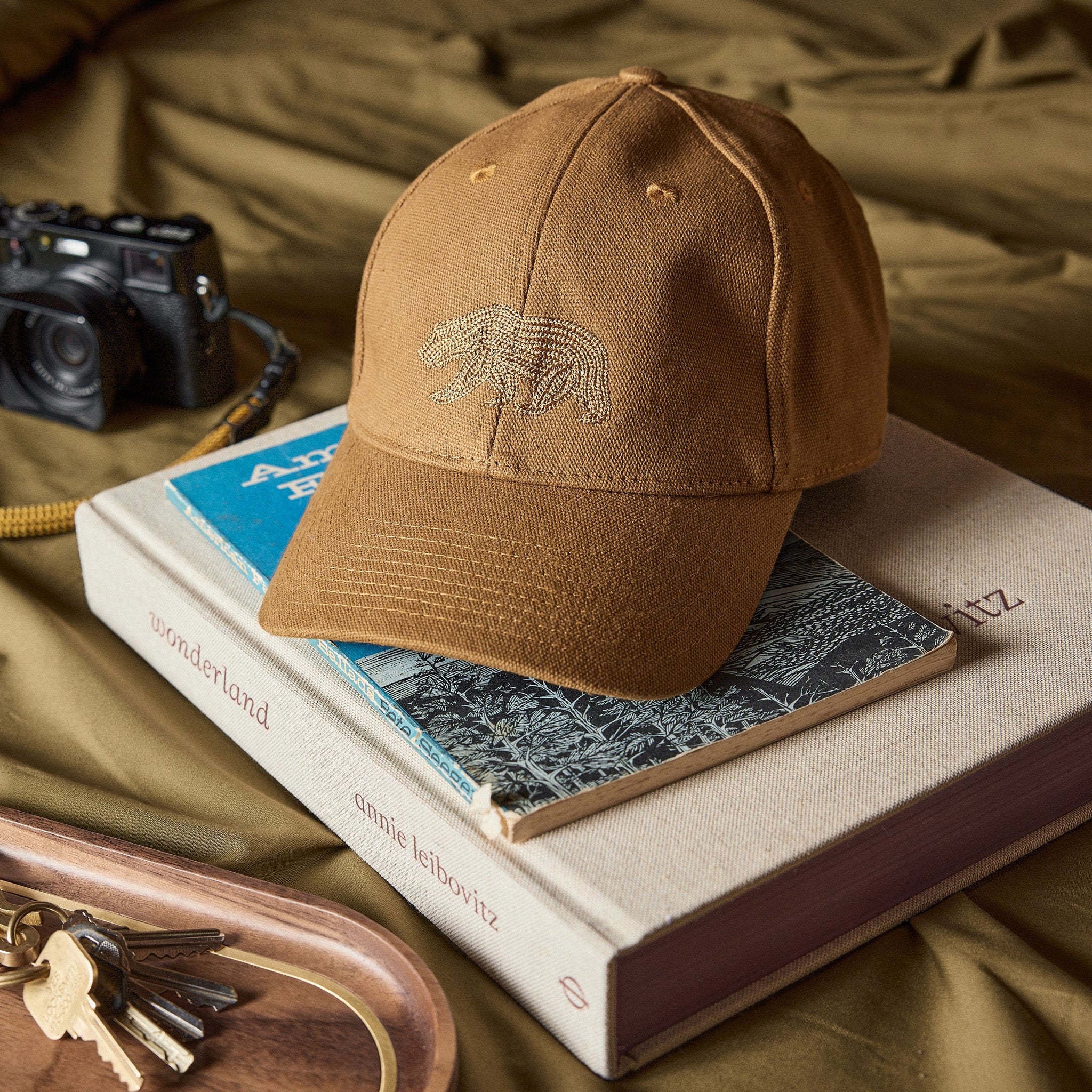 The Ball Cap in Tobacco Canvas on a stack of books, Accessories by Taylor Stitch