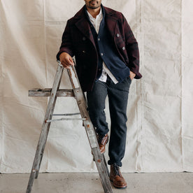fit model leaning against a ladder in The Carnegie Pant in Charcoal Heather Wool