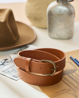editorial image of The Foundation Belt in Whiskey rolled up on paper, Accessories by Taylor Stitch