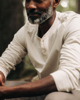 fit model sitting wearing The Heavy Bag Henley in Natural, Knits by Taylor Stitch
