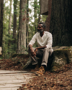 fit model sitting on a log in The Heavy Bag Henley in Natural, Knits by Taylor Stitch