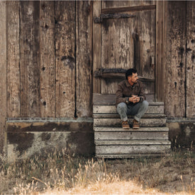 fit model sitting outside a barn in The Longshore Jacket in Aged Penny Chipped Canvas