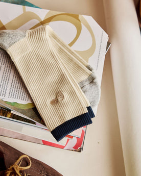 The Ribbed Sock in Natural on a stack of magazines, Accessories by Taylor Stitch