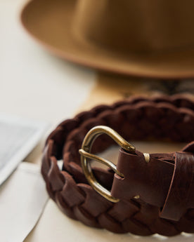 editorial image of The Braided Belt in Dark Brown rolled up on a piece of paper, Accessories by Taylor Stitch