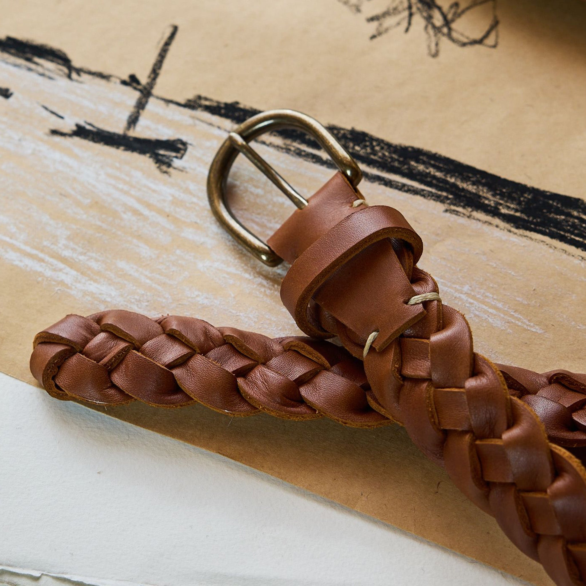 editorial image of the buckle of The Braided Belt in Whiskey on a piece of paper, Accessories by Taylor Stitch