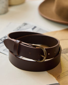 editorial image of The Foundation Belt in Dark Brown rolled up on sheets of paper, Accessories by Taylor Stitch