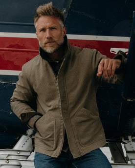 fit model posing on a seaplane wearing The Workhorse Jacket in Stone Chipped Canvas, Outerwear by Taylor Stitch