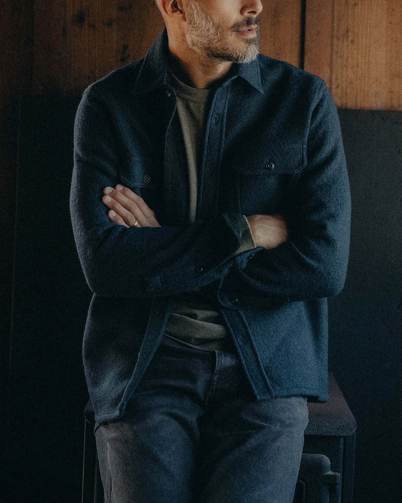fit model leaning against the wall wearing The Connor Overshirt in Dark Navy Boucle, Wovens by Taylor Stitch