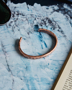 editorial image of The Hammered Cuff in Copper on a marble table, Accessories by Taylor Stitch