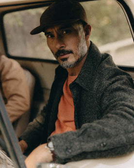fit model sitting wearing The Connor Overshirt in Heather Olive Boucle, Wovens by Taylor Stitch